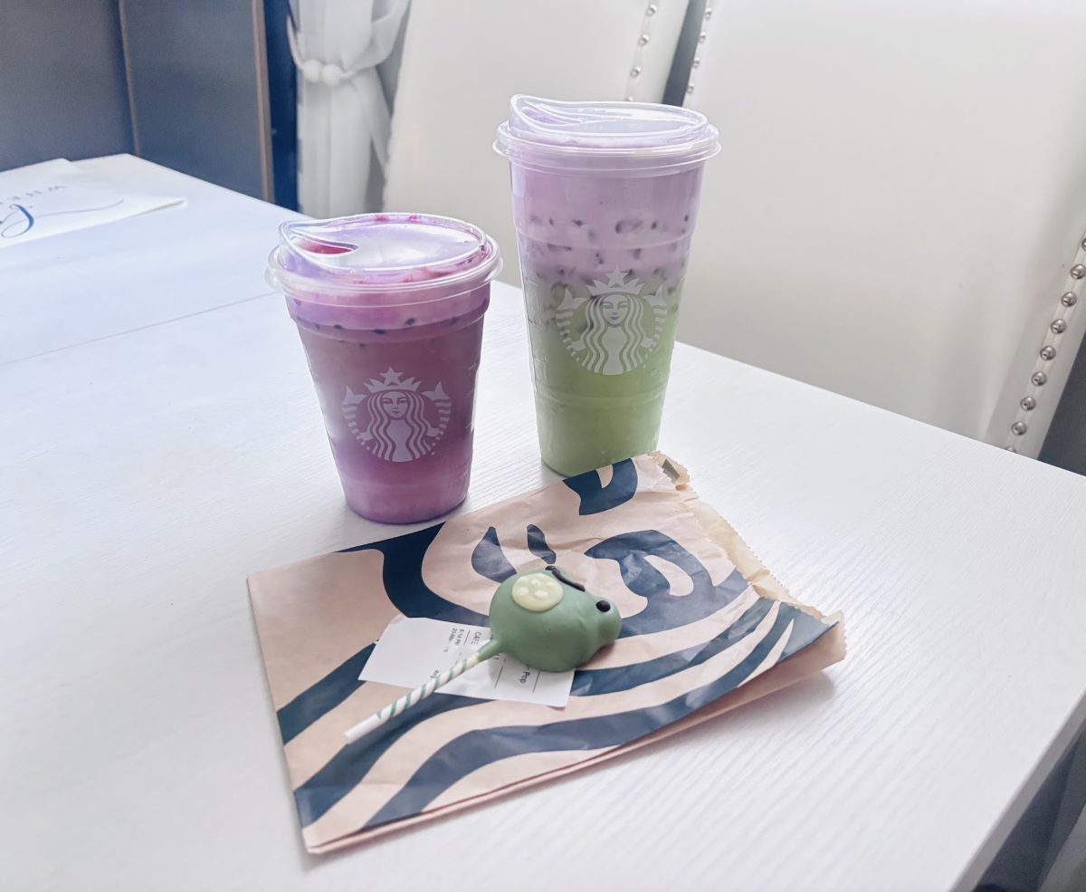 On a white table are displayed Starbucks’ most popular items from its Spring 2026 menu, including the new Iced Ube Coconut Macchiato, Lavender Matcha, and Frog cakepop.